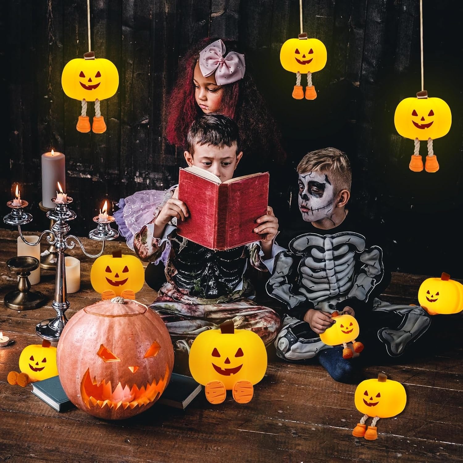 Children in Halloween costumes reading a book with decorative pumpkins and candles